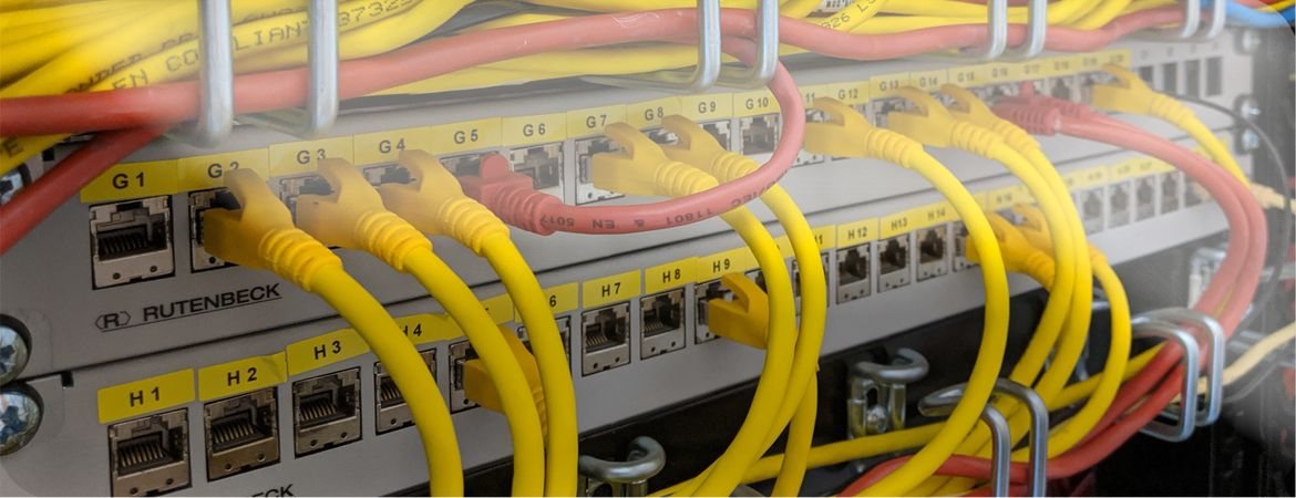 Patchfeld mit beschrifteten Ports, gelb und rot gesteckte Patchkabel in geordneter Kabelführung